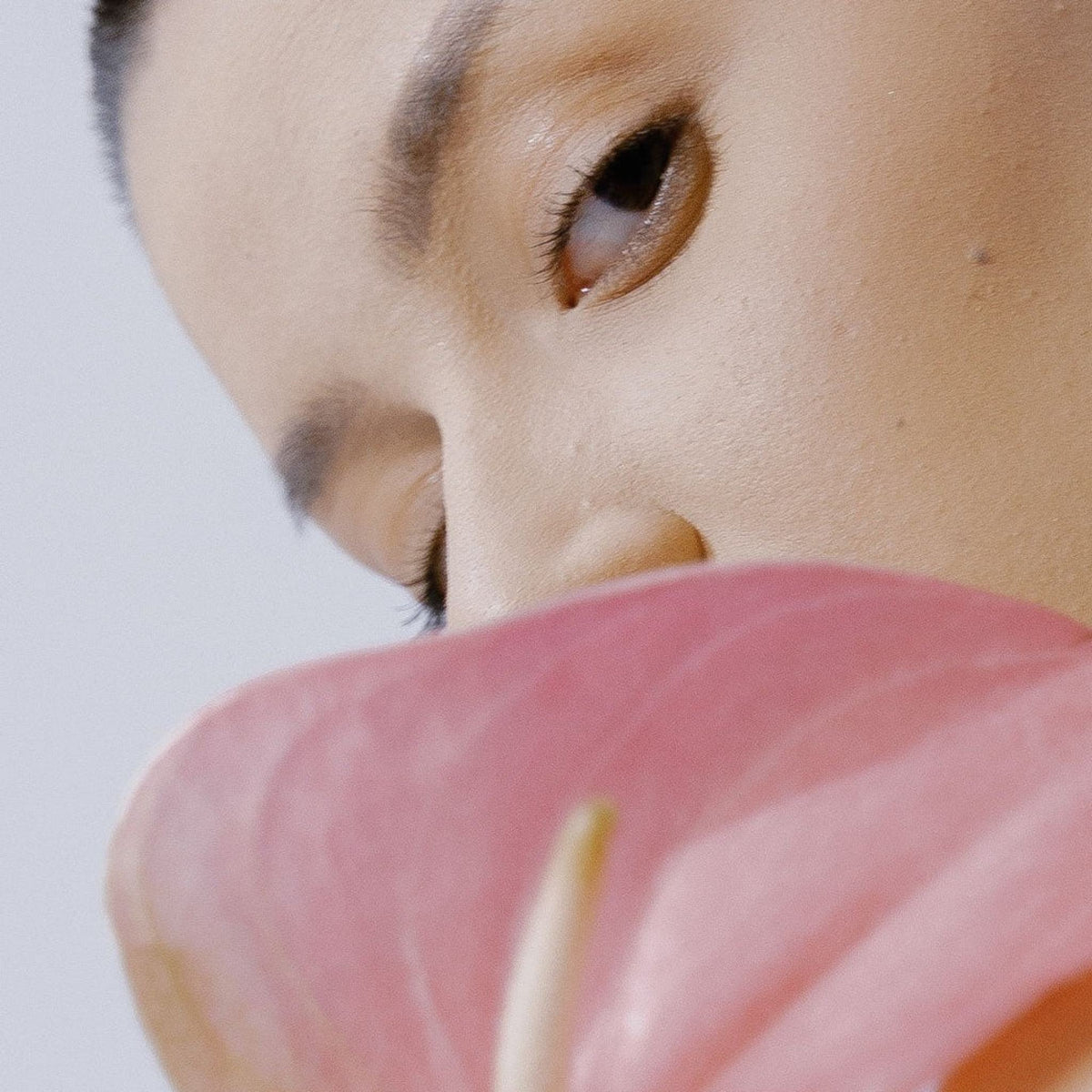 Refect Beauty Dermactive Acti-White Eye Contour applied to a model with glowing skin near a pink anthurium flower