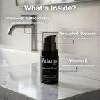 Refect Beauty Adams Signature Beard Oil bottle on a marble bathroom counter with ingredient benefits listed