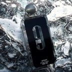 Refect Beauty Afnan 9 PM Eau de Parfum bottle in a sleek black design resting on a textured, icy rock surface.