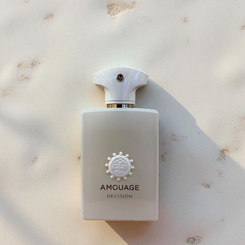 Refect Beauty Amouage Decision Eau de Parfum in a sleek white bottle with a unique emblem on a textured stone surface.