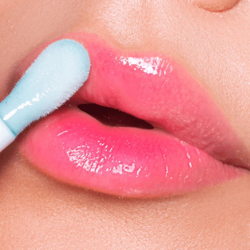 Refect Beauty Astra Pure Beauty Juicy Lip Oil in a glossy pink shade being applied to lips with a soft applicator.