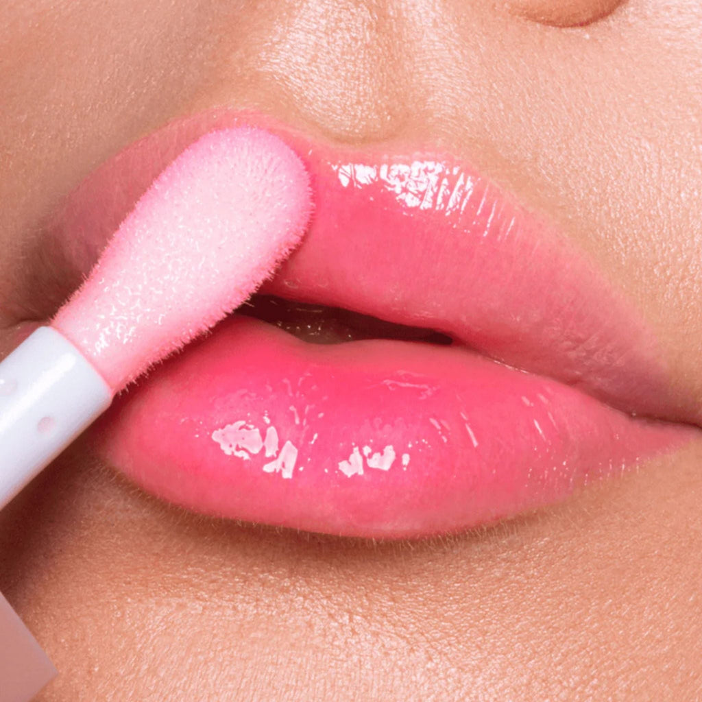 Refect Beauty Astra Pure Beauty Juicy Lip Oil in a glossy pink shade being applied to lips with a soft applicator.