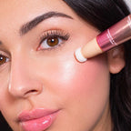 Refect Beauty Astra Light Therapy liquid highlighter applied to a model's cheekbone with a sponge applicator