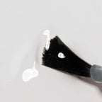 Refect Beauty Astra My Laque nail polish brush with a drop of creamy white lacquer on a smooth surface
