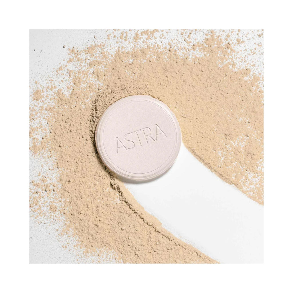 Refect Beauty Astra Natural Skin Powder in a compact case surrounded by loose beige face powder on a white background