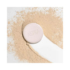 Refect Beauty Astra Natural Skin Powder in a compact case surrounded by loose beige face powder on a white background