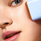 Refect Beauty Astra SPF50 Stick Solare Viso being applied to a model's cheek for invisible sun protection.