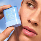 Refect Beauty Astra SPF50 Stick Solare Viso held by a model against a blue sky background for sun protection