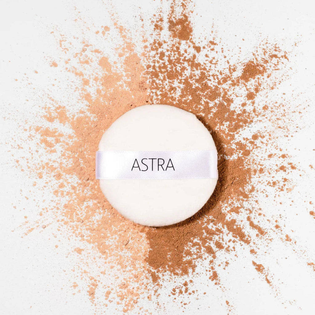 Refect Beauty Astra Velvet Skin loose powder puff surrounded by light and dark beige powder pigments on white surface