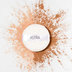 Refect Beauty Astra Velvet Skin loose powder puff surrounded by light and dark beige powder pigments on white surface