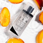 Refect Beauty Astra Zen Routine Fixing Spray bottle surrounded by fresh peach slices and water droplets