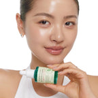 Refect Beauty model holding AXIS-Y Artichoke Intensive Skin Barrier Ampoule serum bottle against a white background