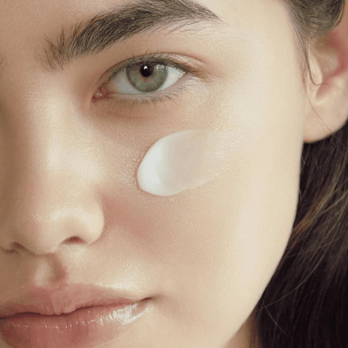 Refect Beauty AXIS-Y TXA 2.5% Intensive Brightening Cream applied as a white balm on a model's cheek for skin care