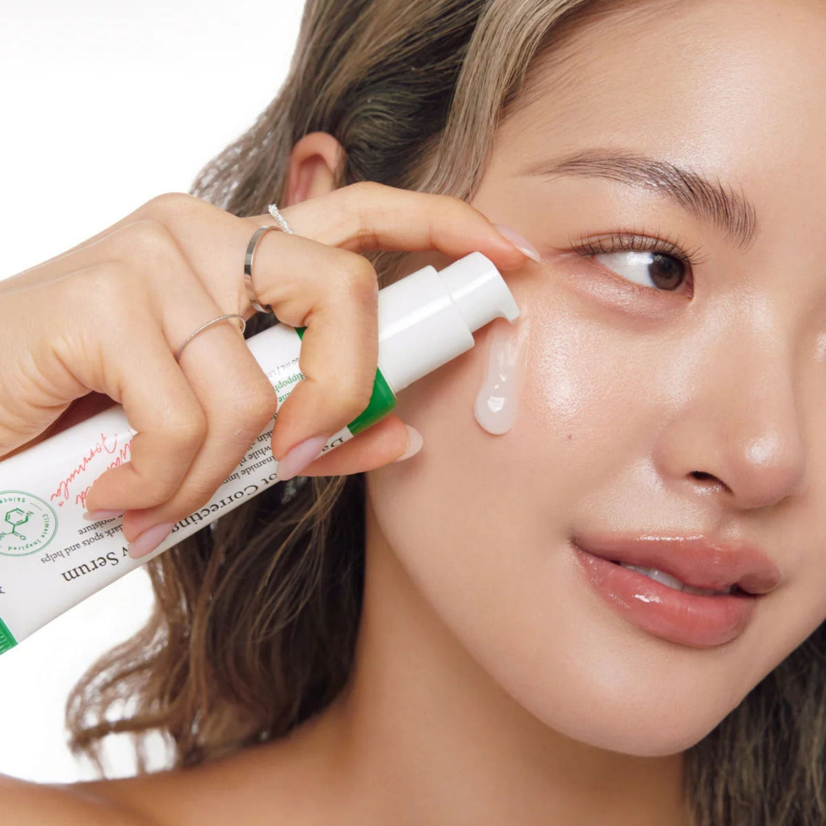 Refect Beauty model applying AXIS-Y Dark Spot Correcting Glow Serum to her cheek for a radiant complexion.