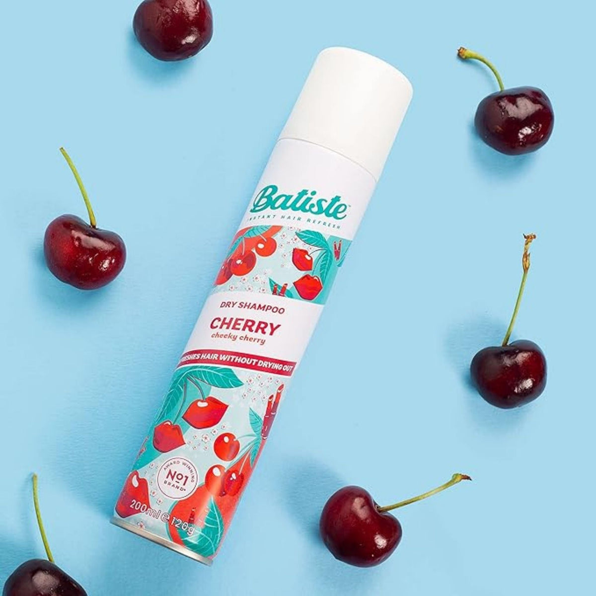 Refect Beauty Batiste Fruity & Cheeky Cherry dry shampoo spray can surrounded by fresh cherries on a blue background.