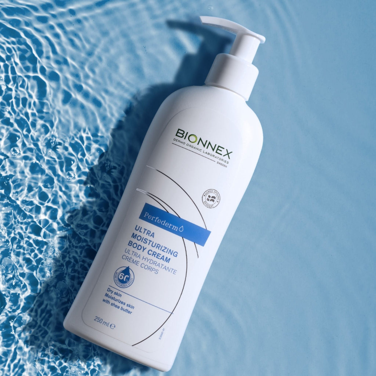 Refect Beauty Bionnex ultra moisturizing body cream in a white pump bottle resting on rippling blue water.