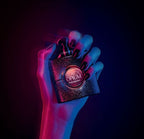 Refect Beauty Yves Saint Laurent Black Opium Neon perfume bottle held by a hand in vibrant neon pink and blue lighting