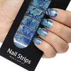Refect Beauty Yolo nail strips with a blue and silver glitter marble design applied to a hand for a salon manicure