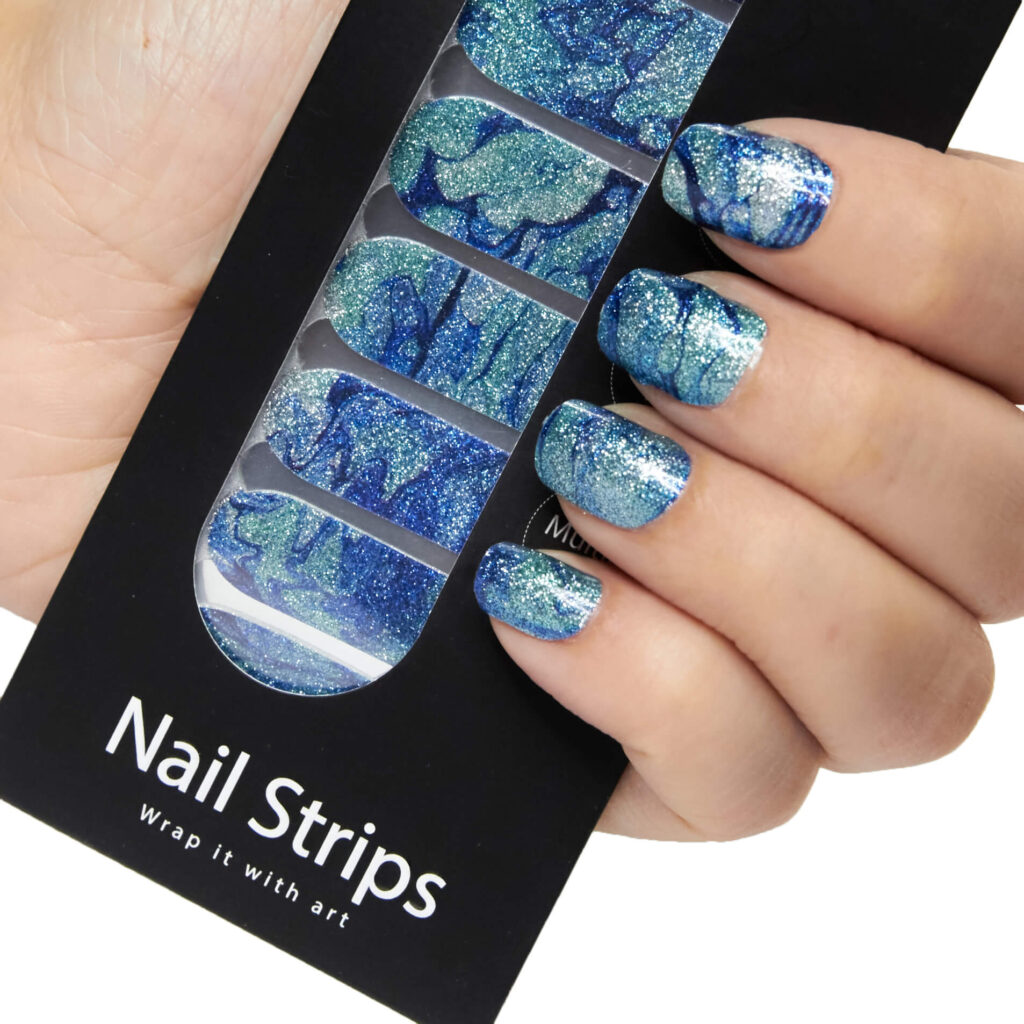 Refect Beauty Yolo nail strips with a blue and silver glitter marble design applied to a hand for a salon manicure