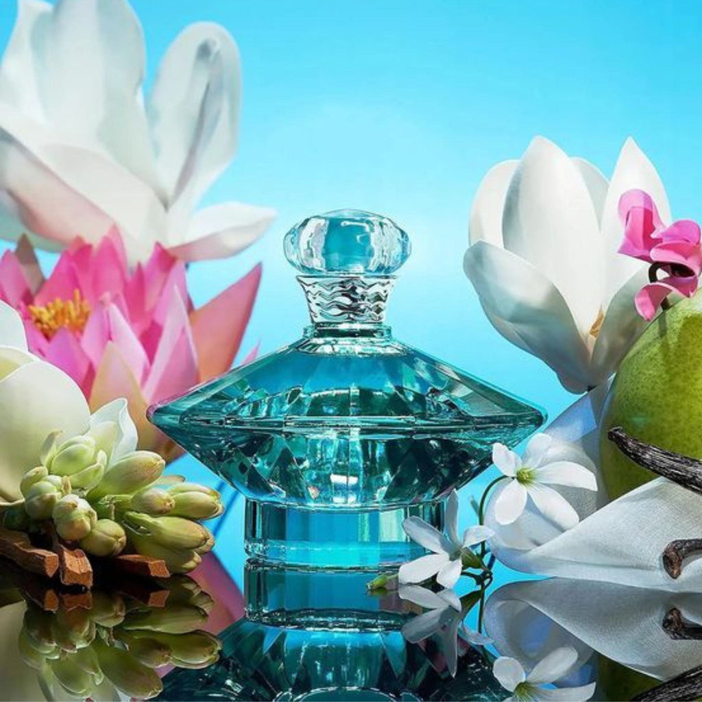 Refect Beauty Britney Spears Curious eau de parfum in a faceted blue glass bottle surrounded by tropical flowers