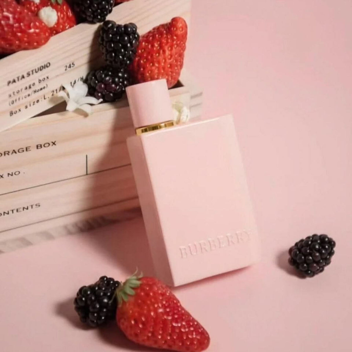Refect Beauty Burberry Her Elixir perfume bottle in light pink with fresh strawberries and blackberries on a pink table