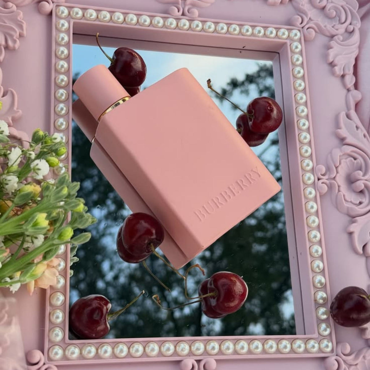 Refect Beauty Burberry Her Elixir perfume bottle in matte pink on a pearl-framed mirror with fresh cherries