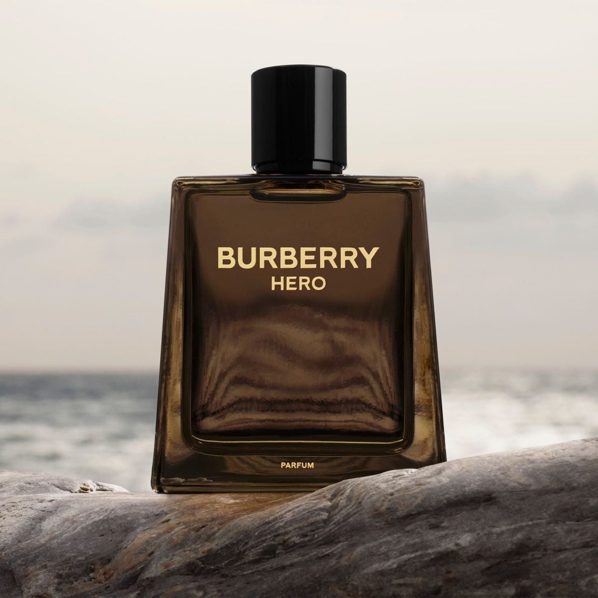 Refect Beauty Burberry Hero Intense Parfum bottle with a dark glass design, set against a natural rocky seascape.