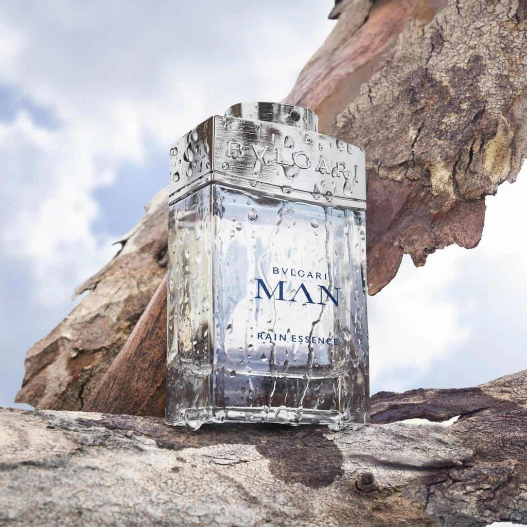 Refect Beauty Bvlgari Man Rain Essence Eau de Parfum bottle with water droplets on a textured tree bark background