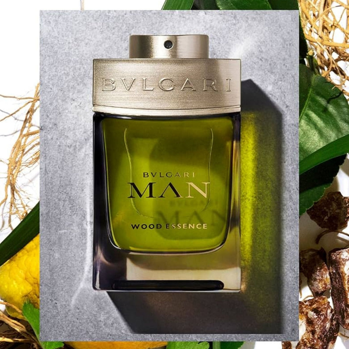 Refect Beauty Bvlgari Man Wood Essence Eau de Parfum in a green glass bottle with metallic cap on a stone background.