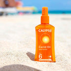 Refect Beauty Calypso Carrot Oil SPF6 deep tanning spray bottle standing in beach sand with a blurred ocean background