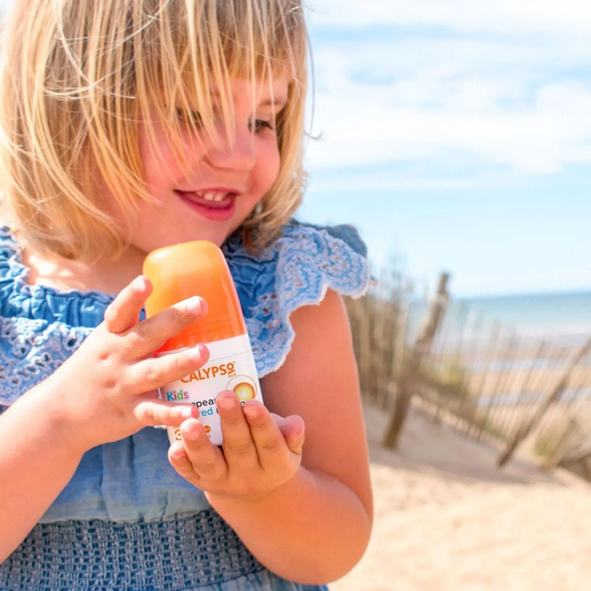 Refect Beauty Calypso Kids SPF30 roll-on sunscreen held by a young girl on a sunny beach
