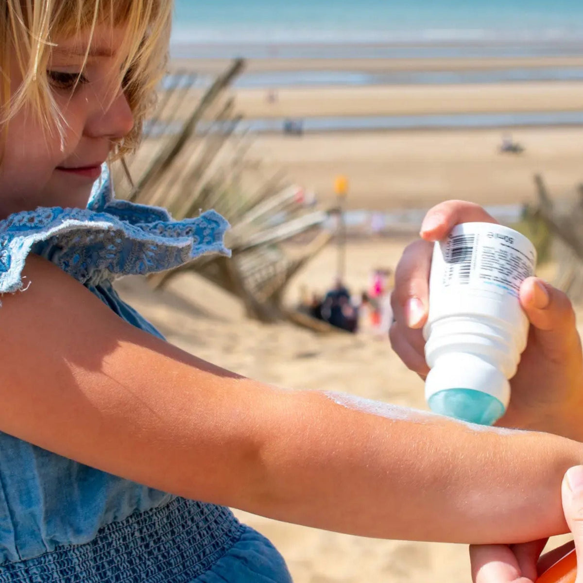 Refect Beauty Calypso Kids SPF30 roll-on sunscreen being applied to a young girl's arm on a sunny beach