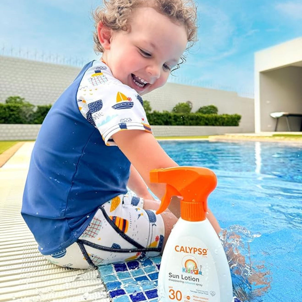 Refect Beauty toddler laughing by a pool next to a bottle of Calypso Kids SPF30 disappearing coloured sun lotion spray