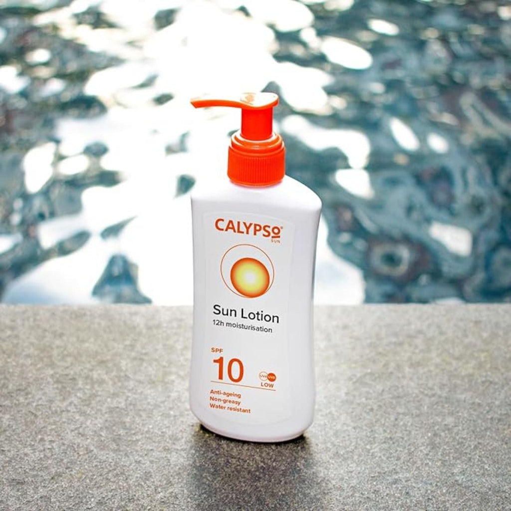 Refect Beauty Calypso Sun Lotion SPF 10 in a white pump bottle, positioned by a swimming pool for outdoor use.