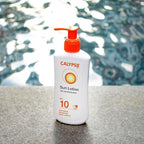 Refect Beauty Calypso Sun Lotion SPF 10 in a white pump bottle, positioned by a swimming pool for outdoor use.