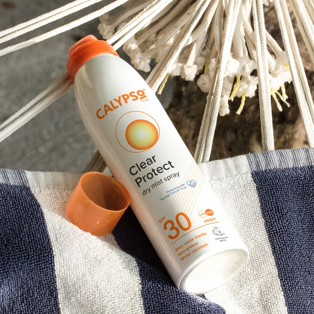 Refect Beauty Calypso Sun Clear Protect SPF 30 dry mist sunscreen spray bottle resting on a blue and white hammock
