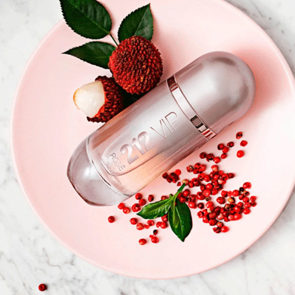Refect Beauty Carolina Herrera 212 VIP Rosé perfume bottle on a pink plate with lychee fruit and pink peppercorns.