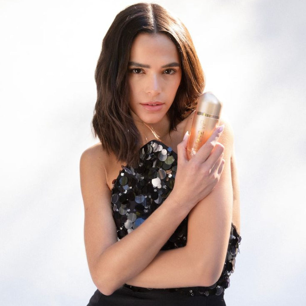 Refect Beauty model holding a bottle of Carolina Herrera 212 VIP Rosé Eau de Parfum in a glamorous sequined dress
