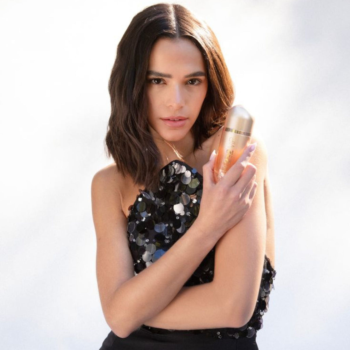 Refect Beauty model holding a bottle of Carolina Herrera 212 VIP Rosé Eau de Parfum in a glamorous sequined dress