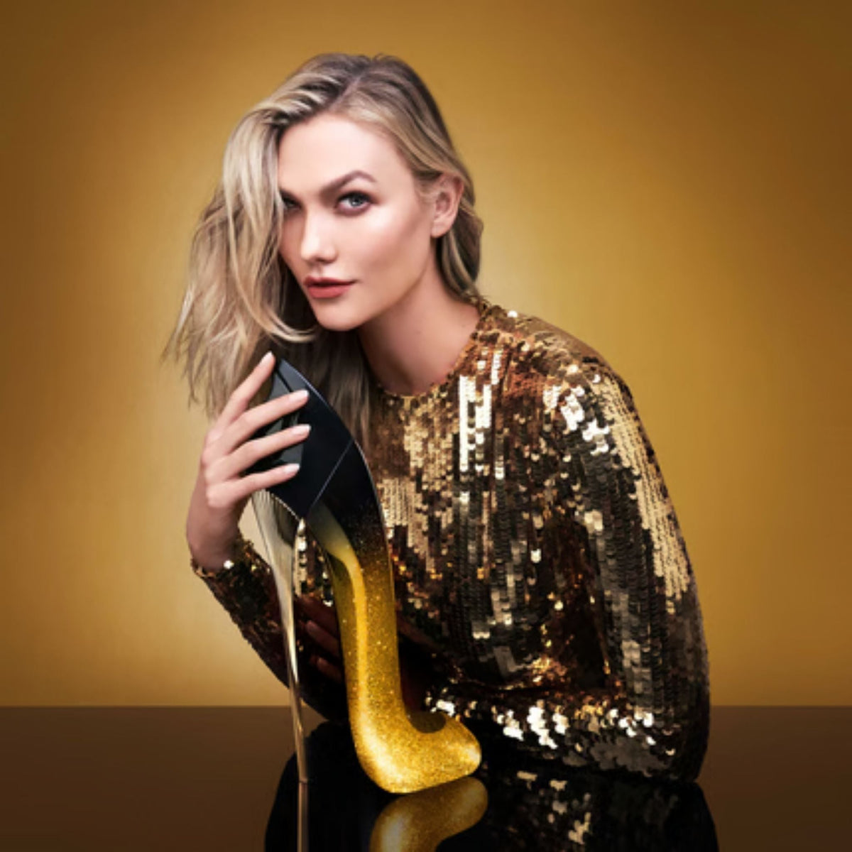 Refect Beauty model posing with a gold and black stiletto-shaped Carolina Herrera Good Girl Midnight perfume bottle