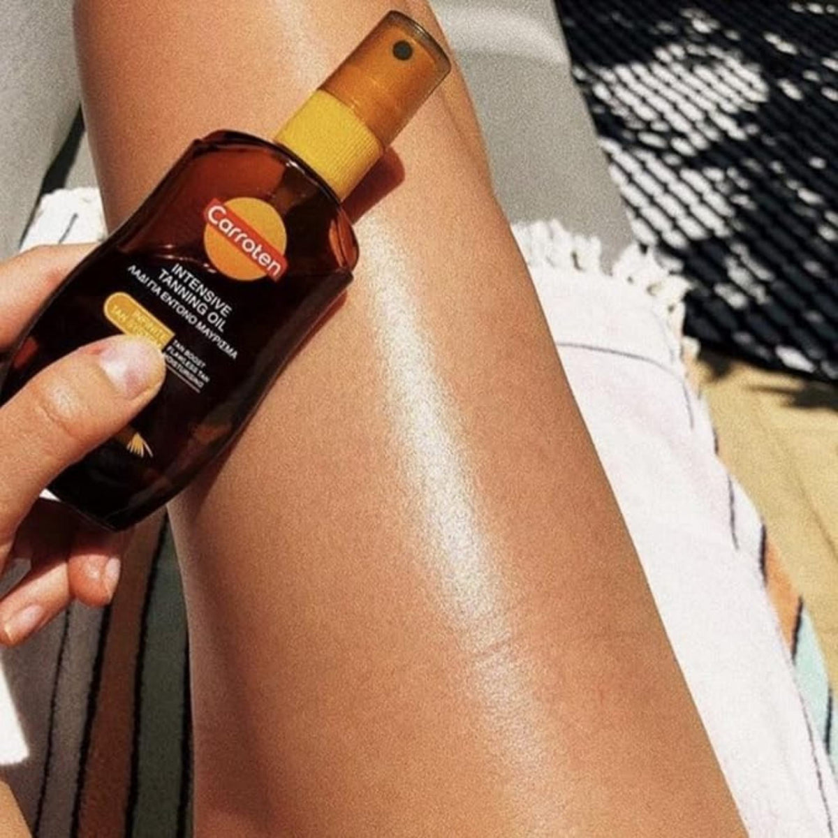Refect Beauty Carroten Intensive Tanning Oil spray bottle held against a sun-kissed, glowing leg outdoors