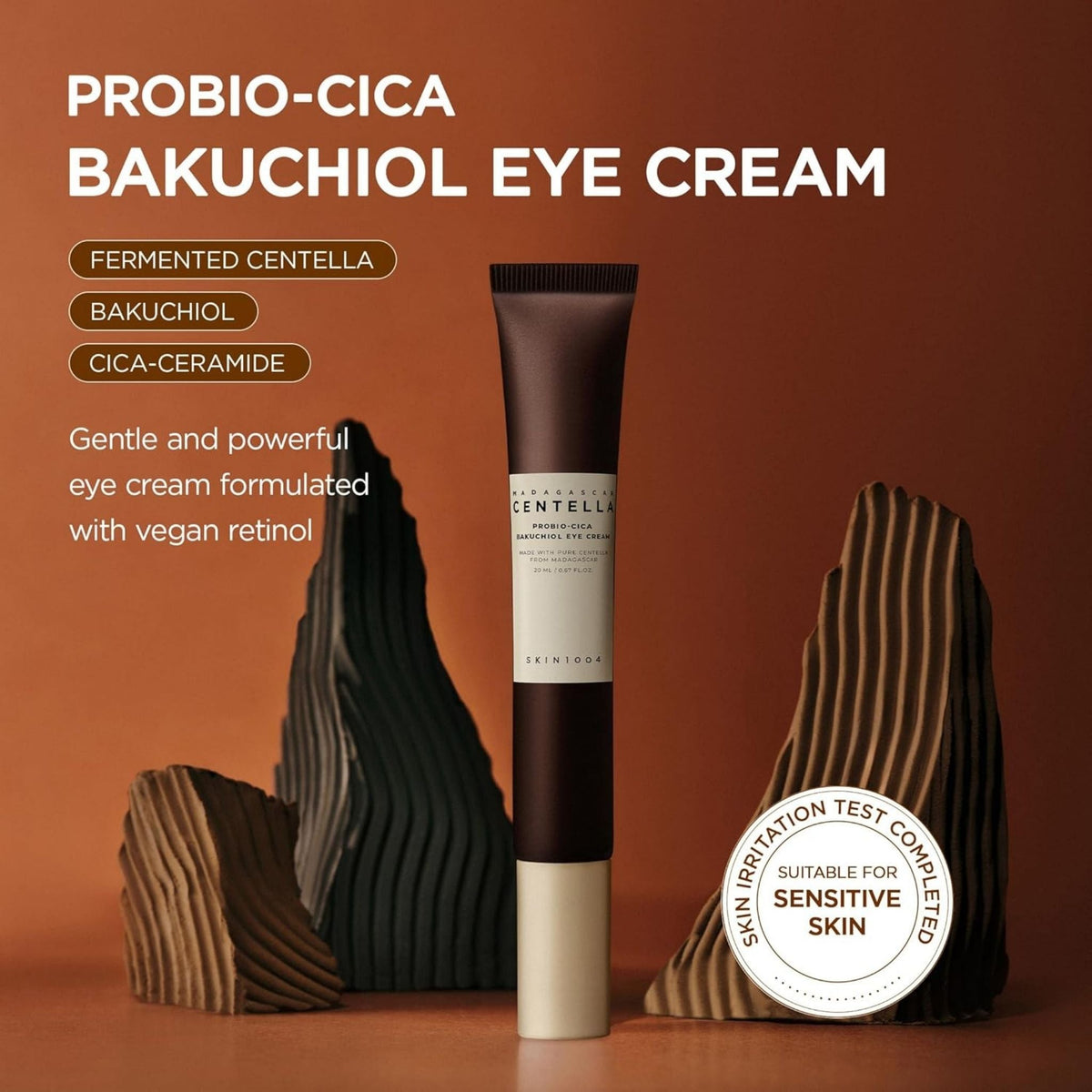 Refect Beauty Centella Probio-Cica Bakuchiol Eye Cream in a brown tube against a warm, textured brown background.
