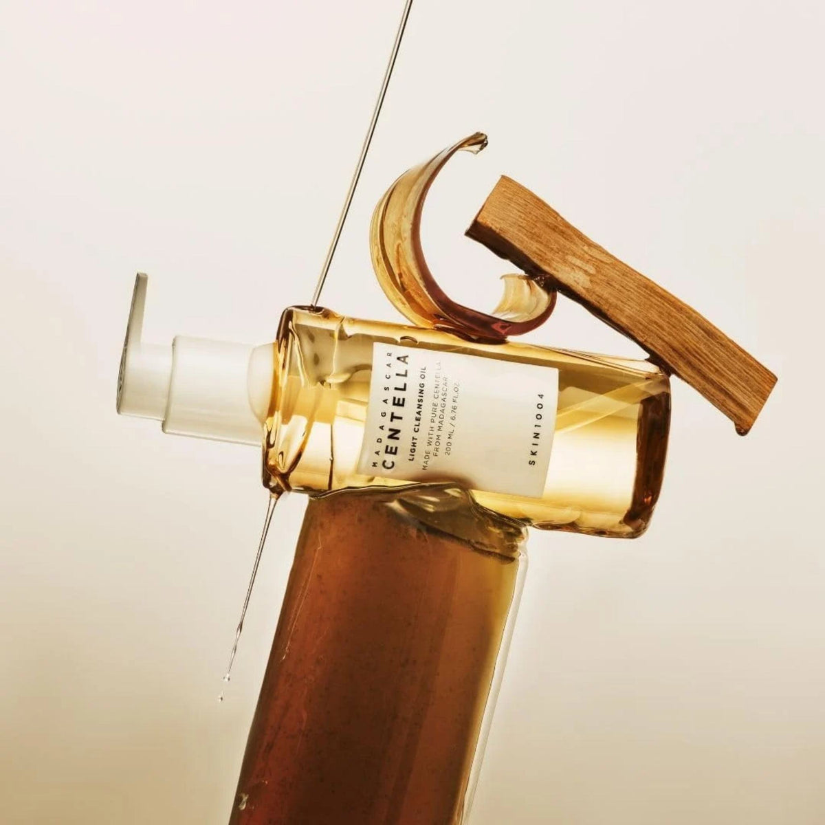 Refect Beauty Centella Light Cleansing Oil bottle with golden oil dripping over a wooden block on a neutral background