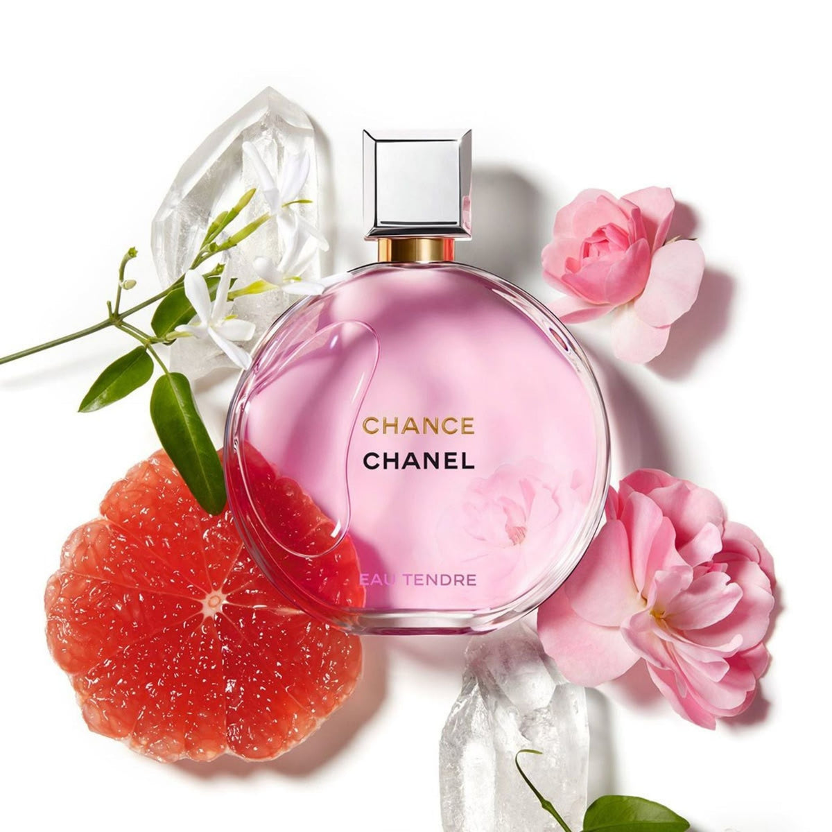 Refect Beauty Chanel Chance Eau Tendre perfume bottle surrounded by pink flowers, grapefruit slices, and crystals.