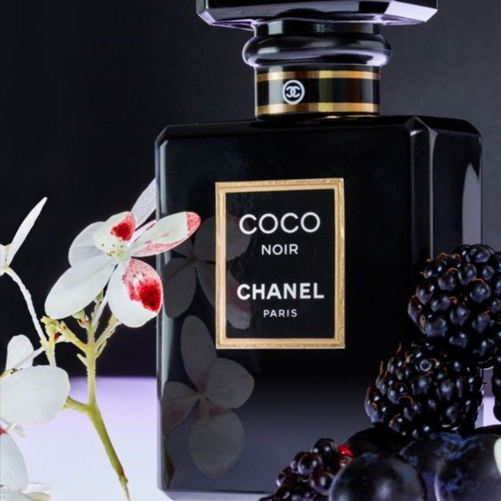 Refect Beauty Chanel Coco Noir Eau de Parfum in a sleek black bottle surrounded by blackberries and white flowers.