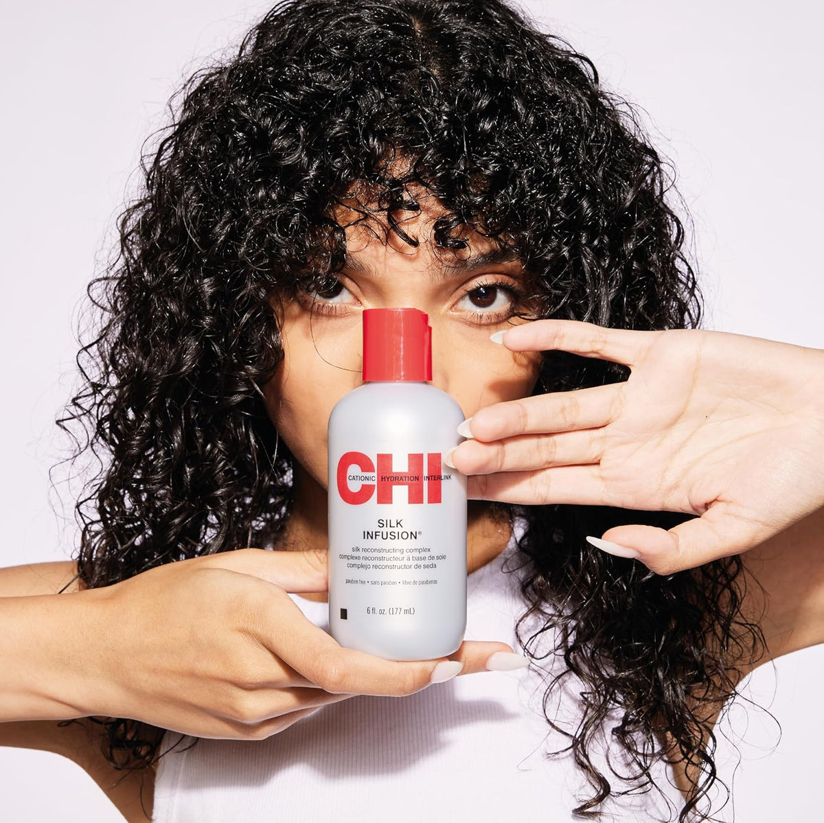 Refect Beauty model holding a bottle of CHI Silk Infusion leave-in hair serum for smooth and shiny hair