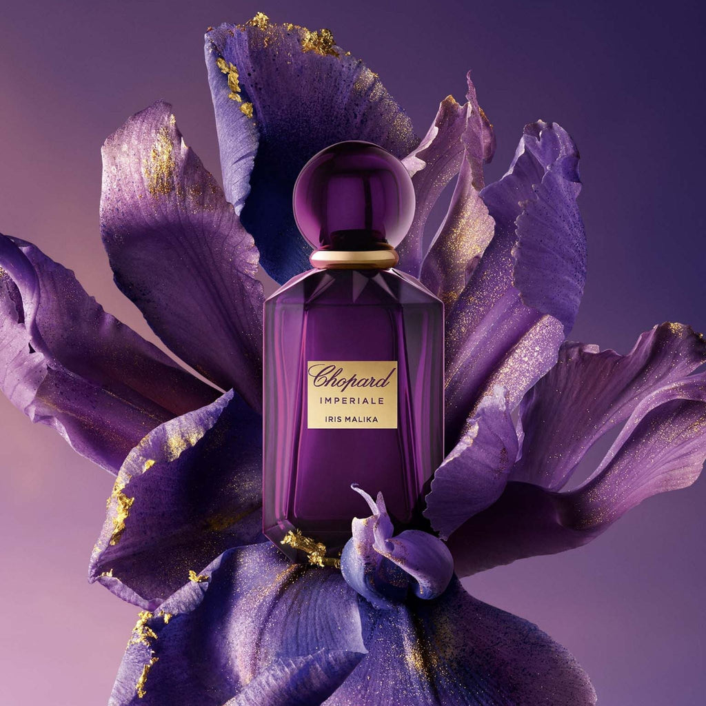 Refect Beauty Chopard Imperiale Iris Malika perfume bottle resting on a large purple iris flower with gold accents