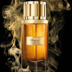 Refect Beauty Chopard Oud Malaki Eau de Parfum bottle surrounded by swirling golden smoke on a black background.