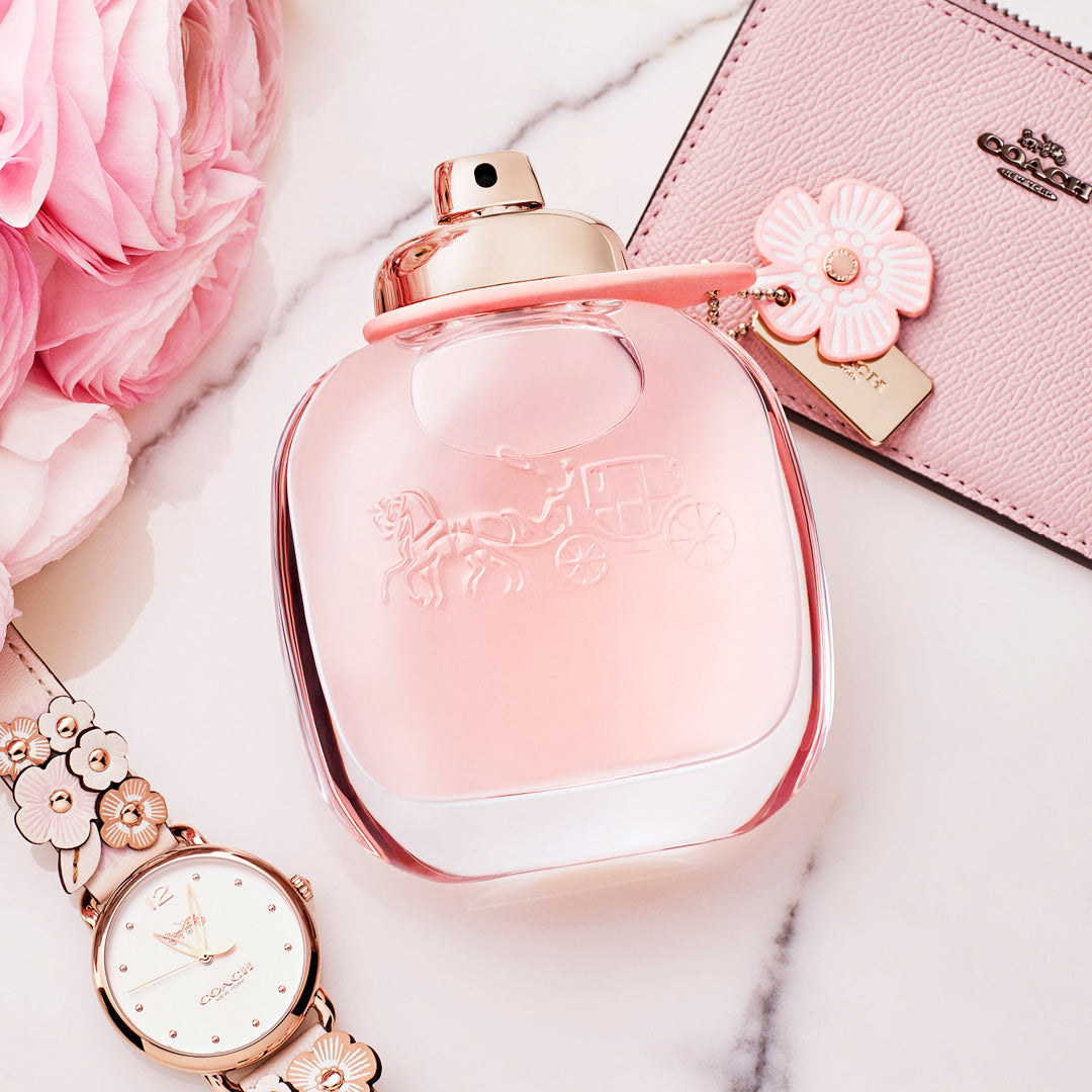 Refect Beauty Coach Floral Eau de Parfum bottle with pink liquid, floral charm, and matching watch on marble surface