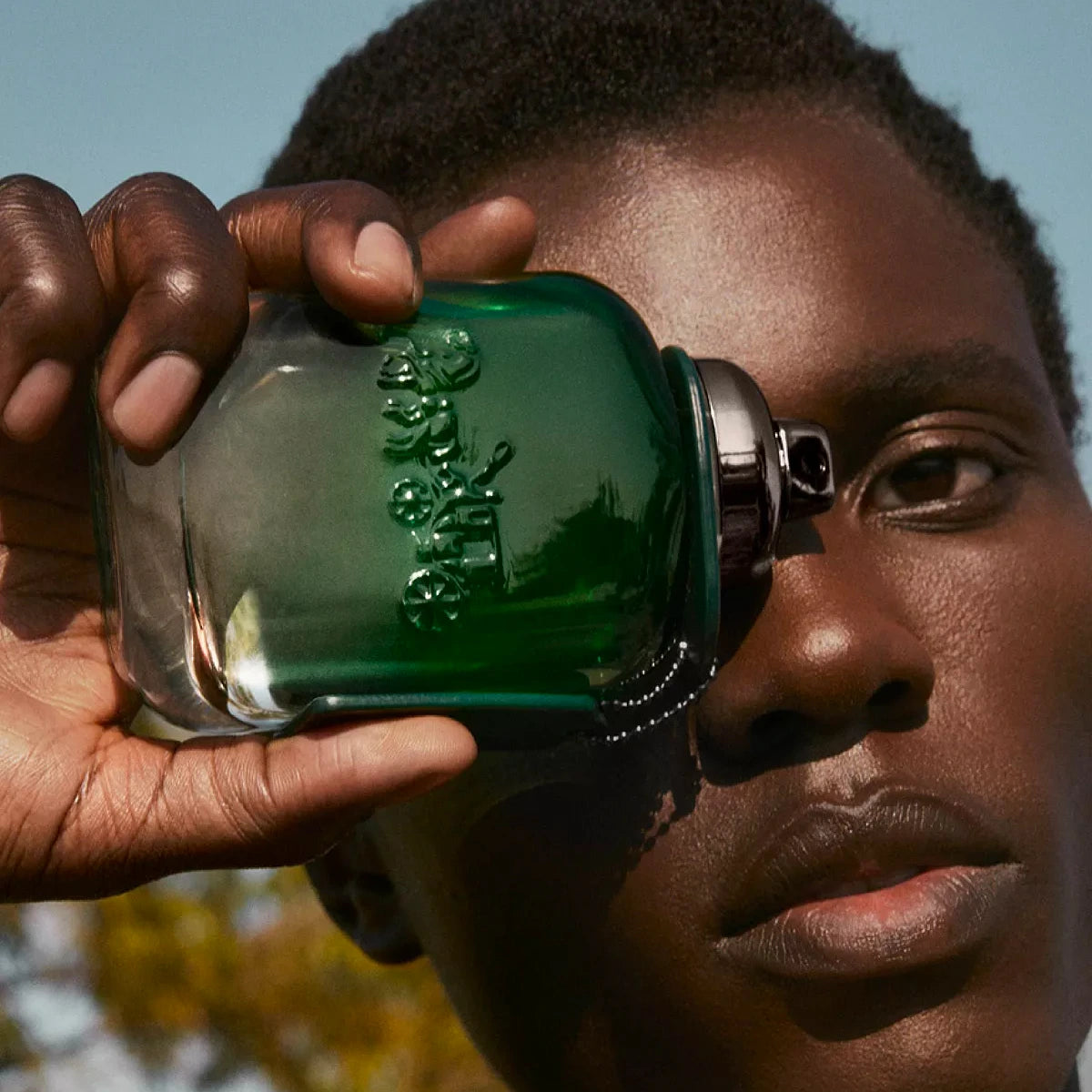 Refect Beauty Coach Green for Men Eau de Toilette bottle held by a man against his face in a sunny outdoor setting